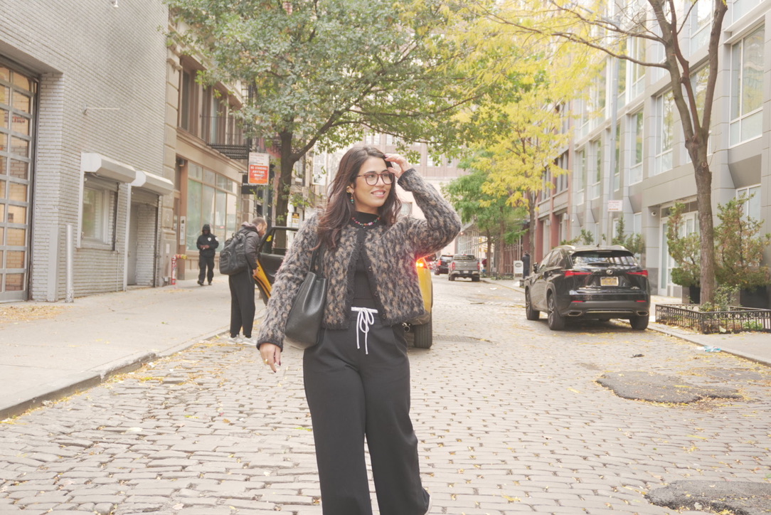 Annette sonriendo en una calle empedrada, con la mano en el pelo
