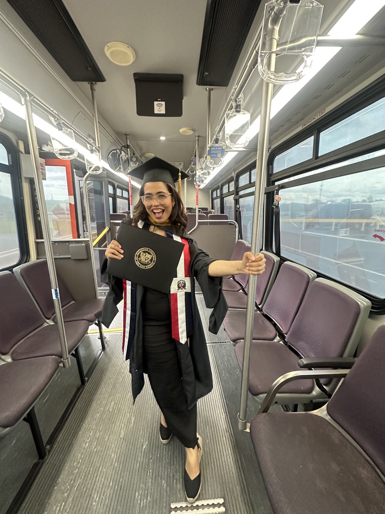 Annette con toga y birrete, celebrando con su diploma en un autobús