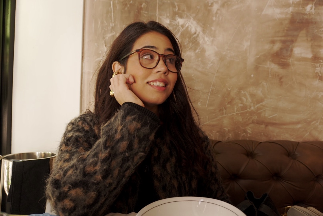 Annette sonriendo, con lentes y un suéter de animal print